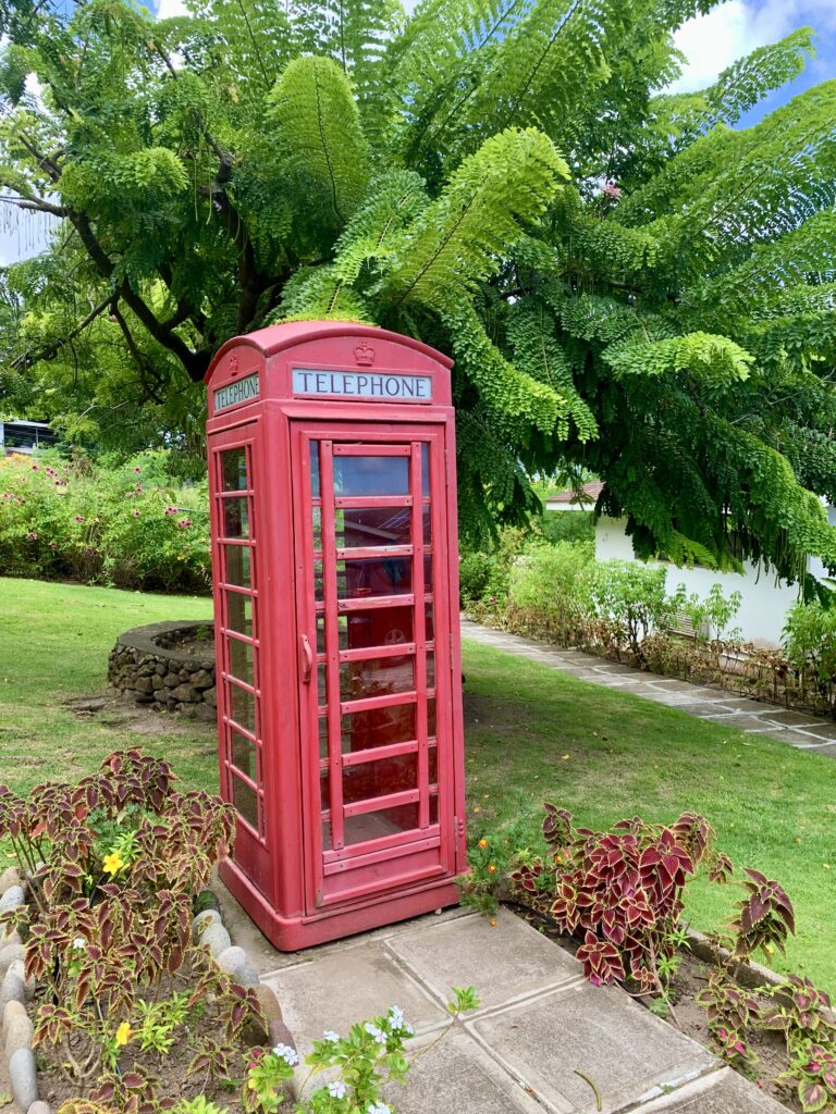 Bright red British phone booth in a lush, green, tropical garden