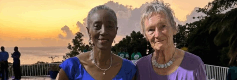 Two women wearing cocktail dresses posing in front of a sunset